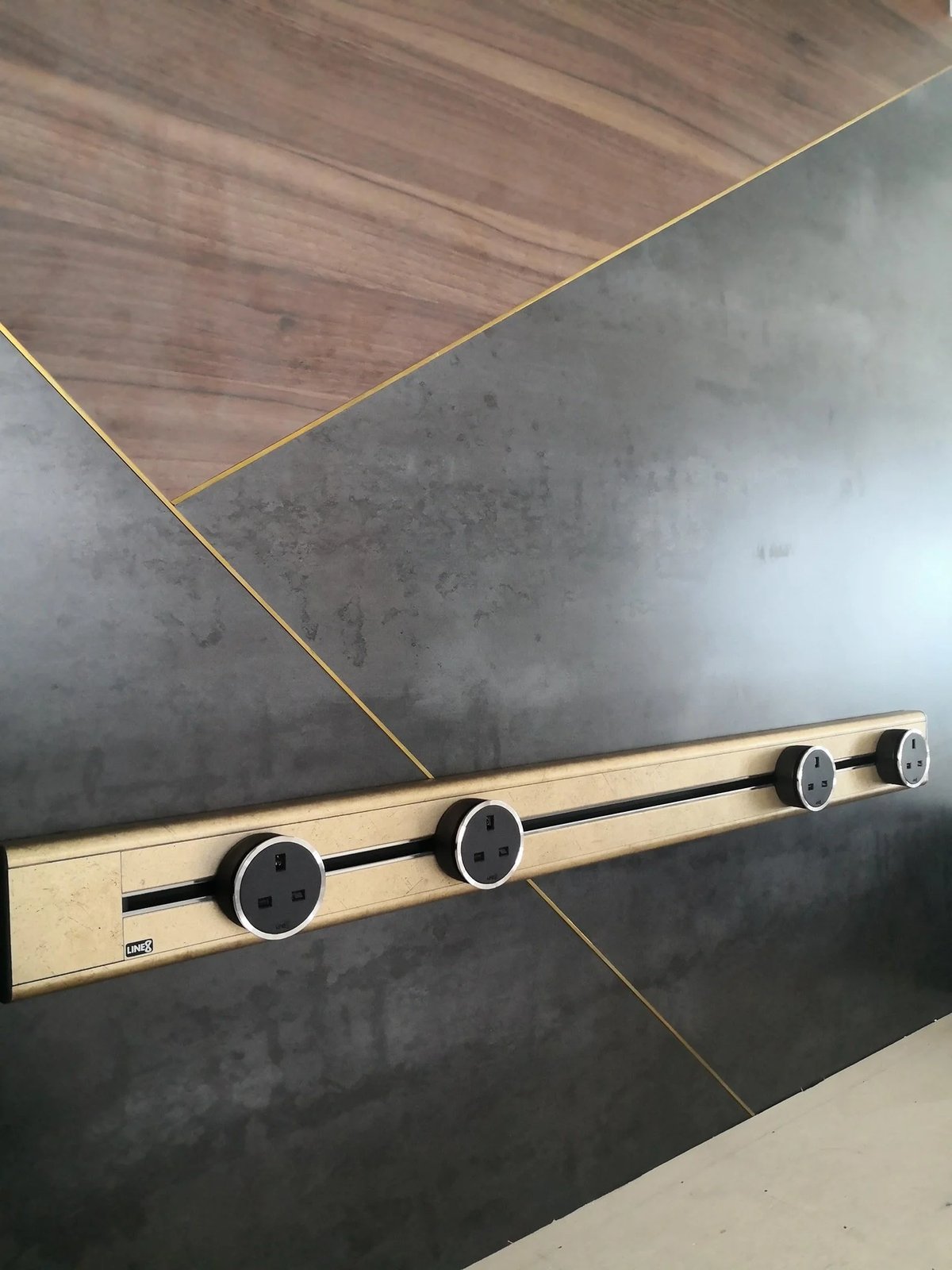 Line8 Model SL track in Champagne Gold mounted on a wall, powering multiple sockets