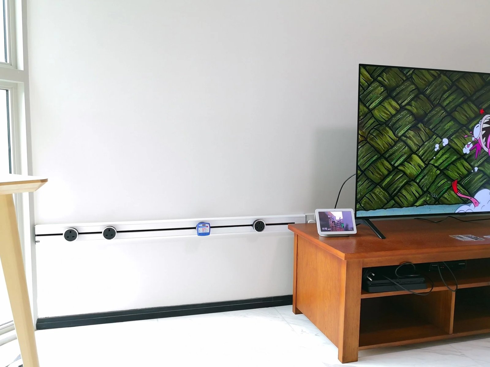 Line8 Model SL track in Black Hairline along a living room wall powering a TV and devices