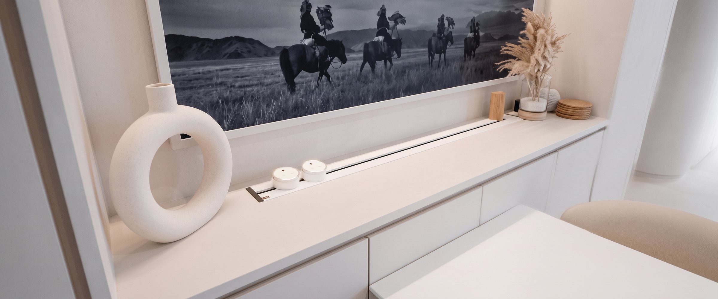 Two white Line8 UKS-1 adaptors recessed into a white credenza, styled with ceramic decor and framed artwork