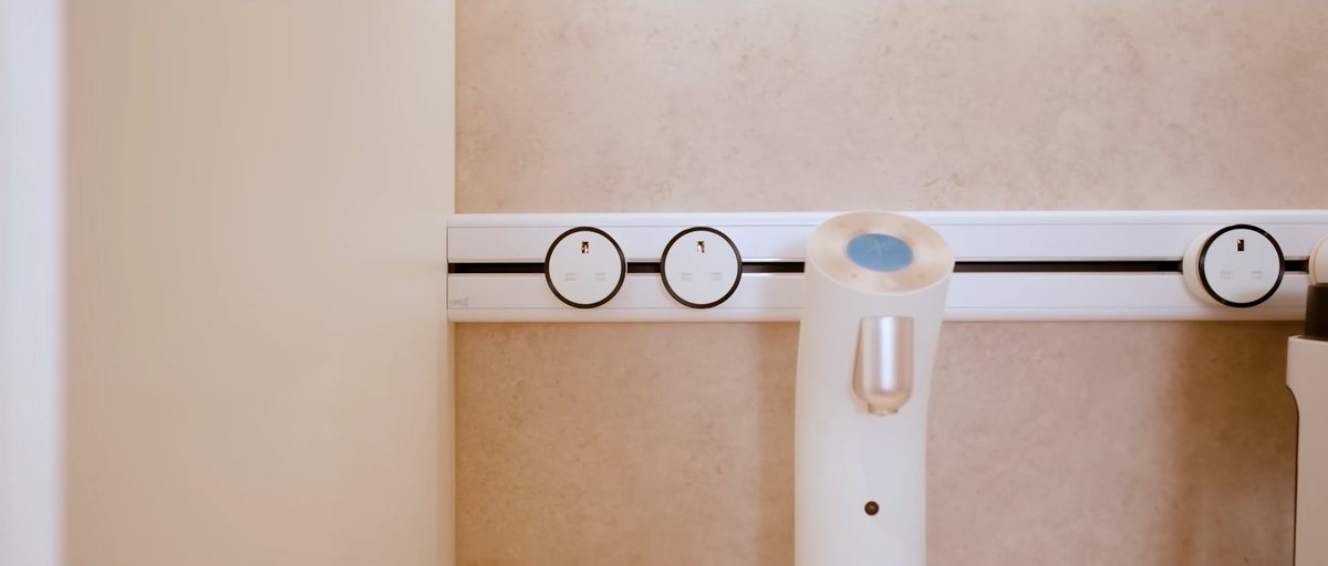 White Line8 adaptors on a track beside a countertop appliance against a warm stone wall