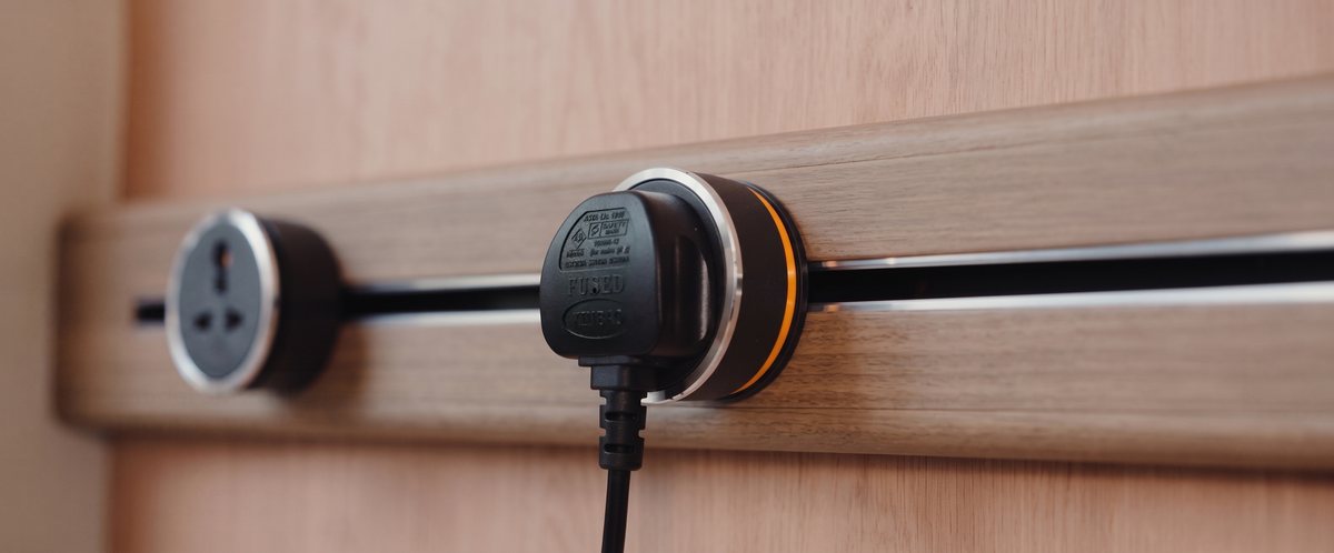 Macro shot of a plug engaged in a Line8 adaptor with an orange finish ring on a wood-finish track