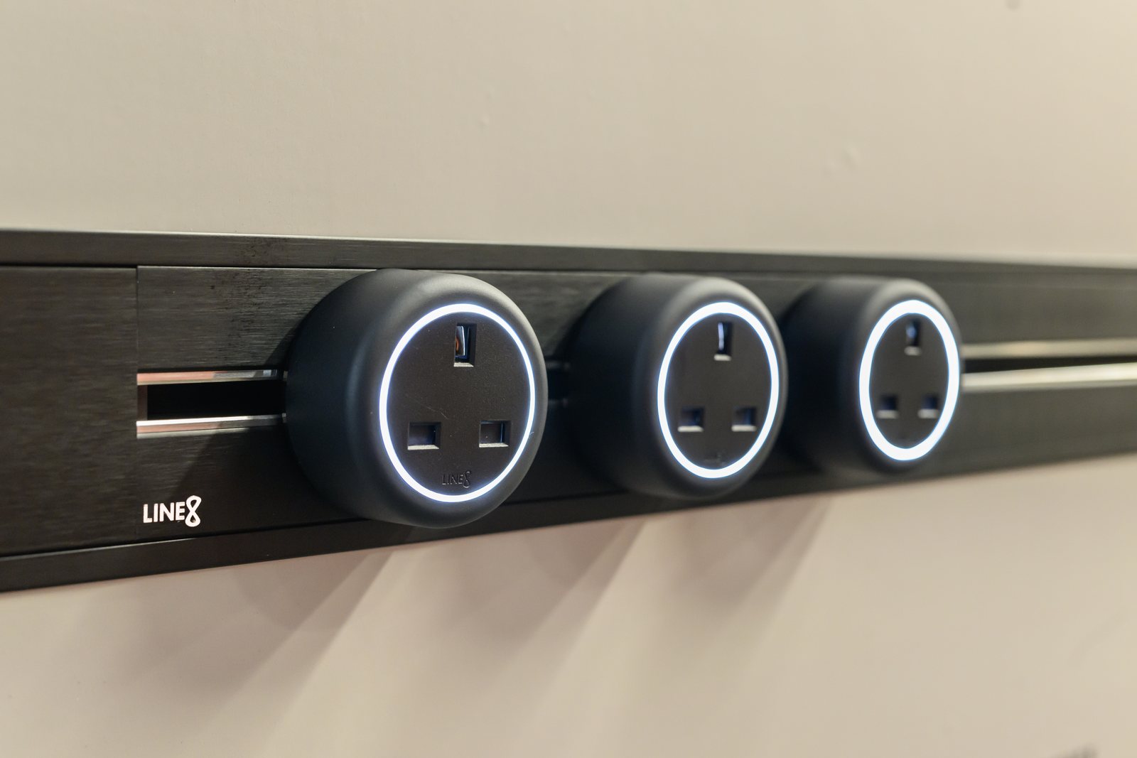 Two black Zen Series adaptors on a Line8 Zen Track, mounted on a dark stone wall