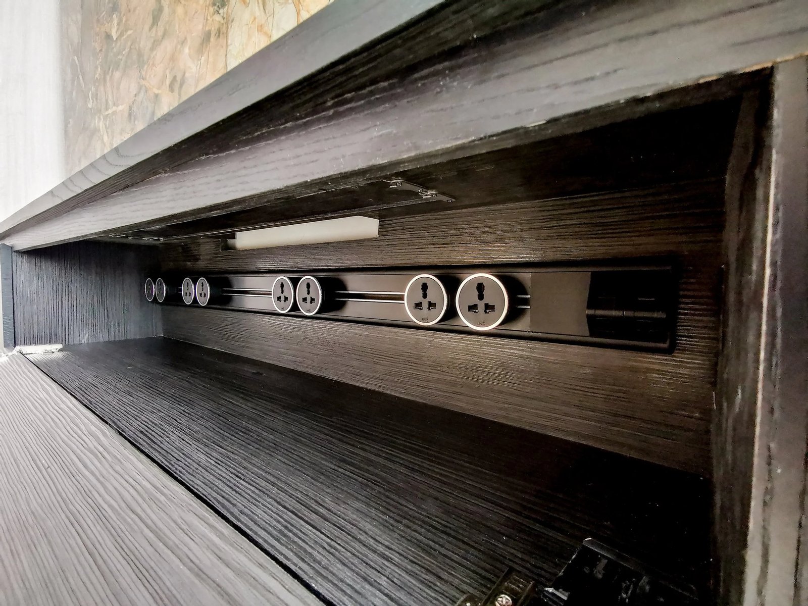 Line8 Model SL track in Black Hairline within a living room cabinet, powering multiple outlets