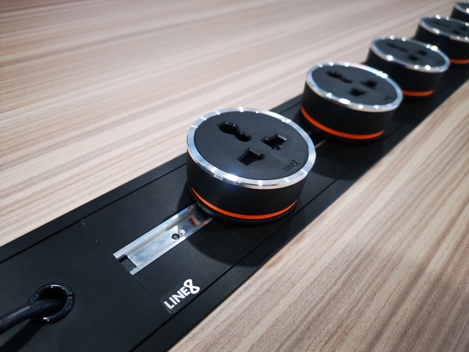 Line8 Model SL track in Black Hairline along a conference table with power sockets