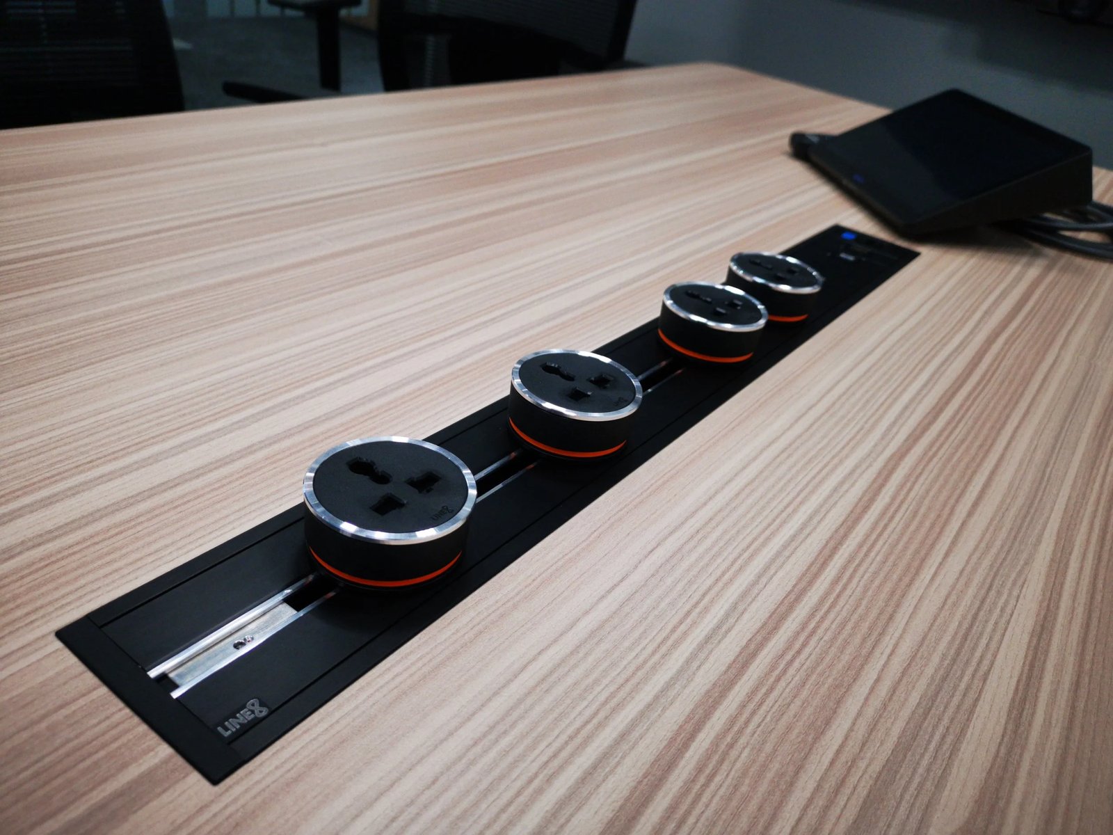 Line8 Model SL track in Black Hairline on a conference table powering multiple outlets