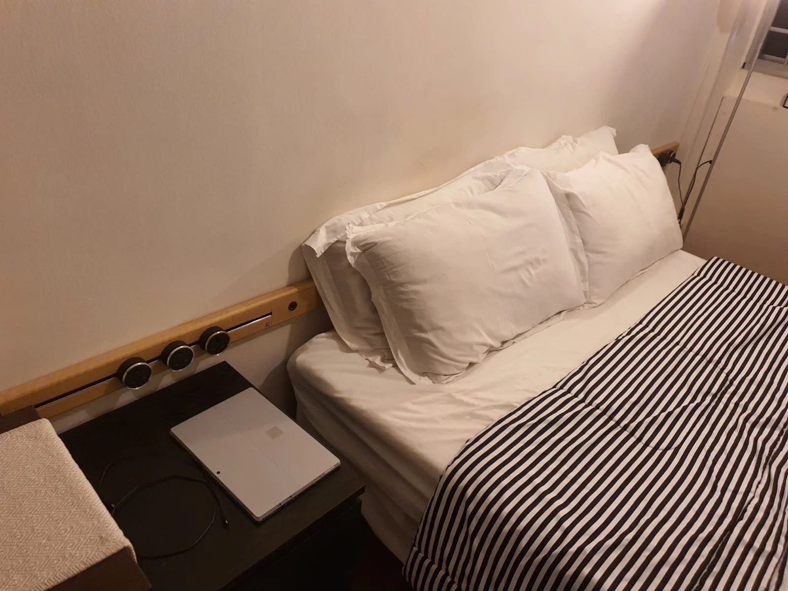 Line8 Model SL track in American Spruce above a bed with white pillows and striped bedding