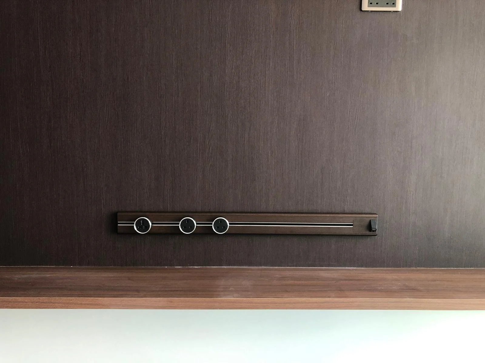 Line8 Model SL track in Black Hairline mounted on a wall above a wooden shelf
