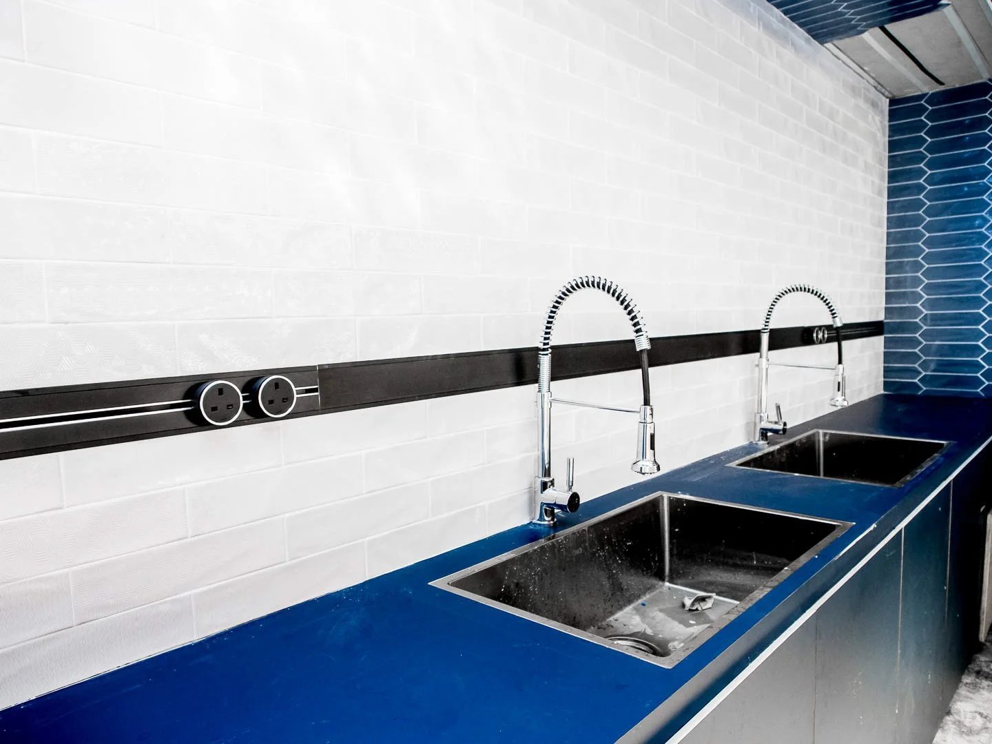 Line8 Model SL track in Black Hairline above a kitchen sink area powering faucets